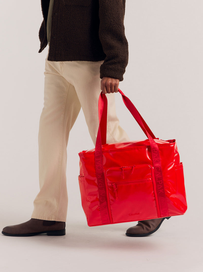 CALPAK Terra 35L Water Resistant Tote in red being held handles by model