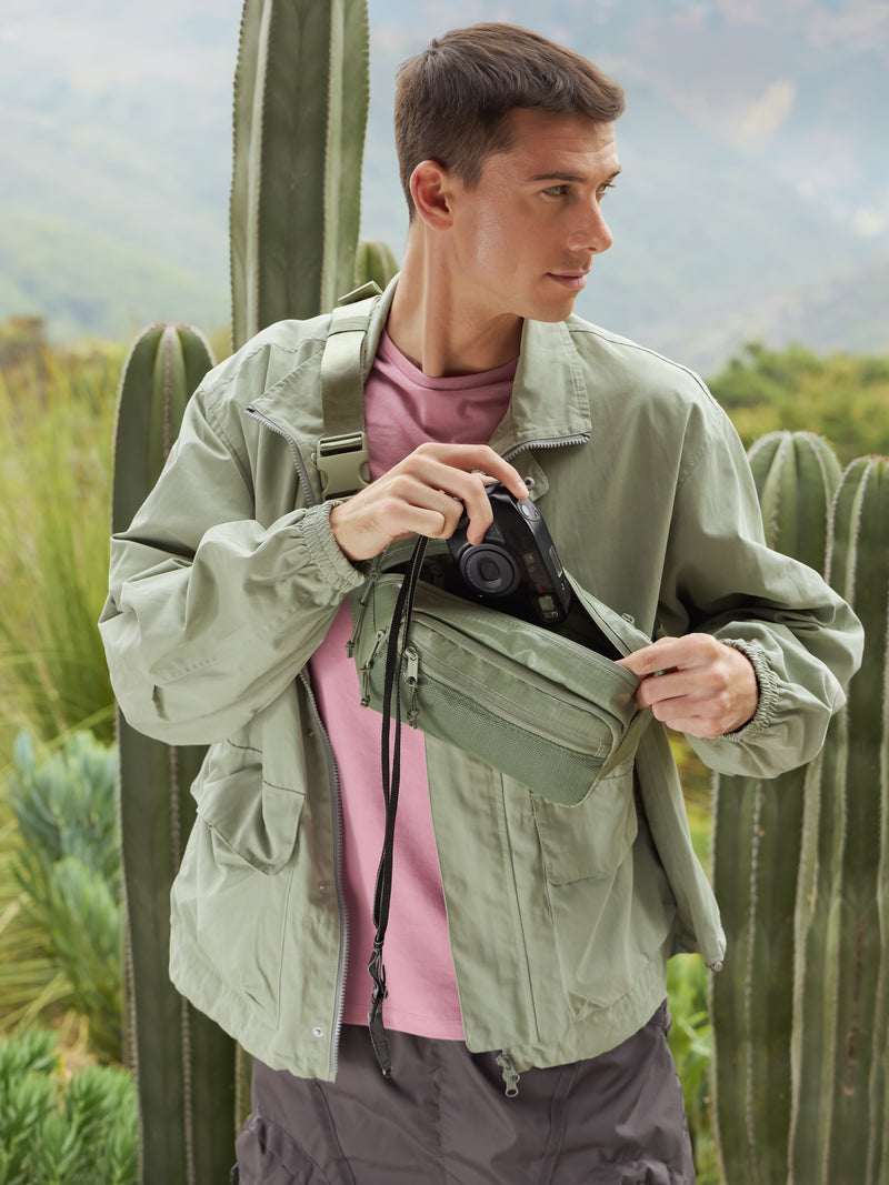 Model wearing CALPAK Terra small belt bag with adjustable strap and mesh front pocket in green