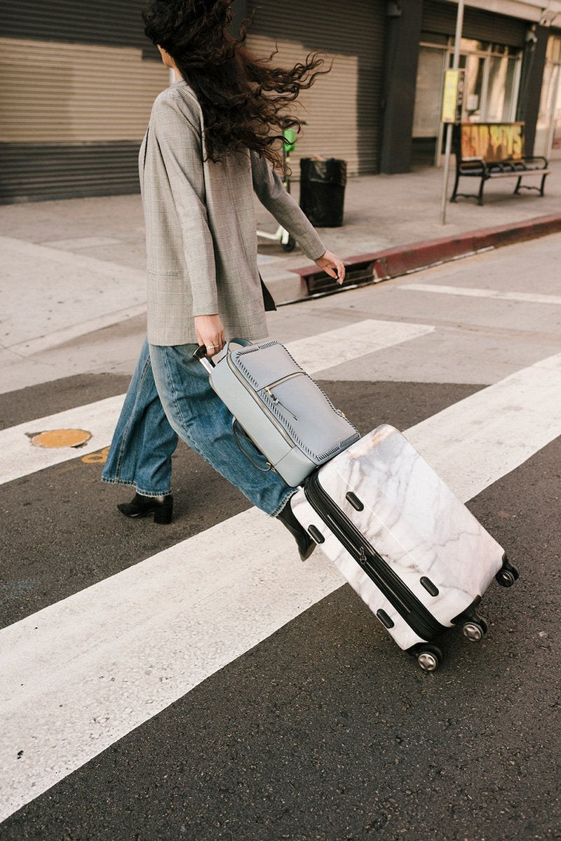 female model with CALPAK Kaya laptop backpack attached to carry on